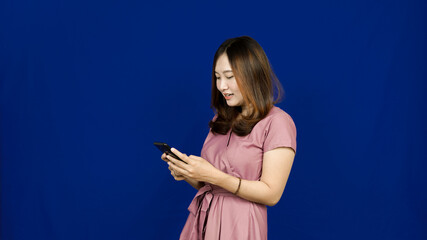beautiful asian woman smile see handphone isolated blue background