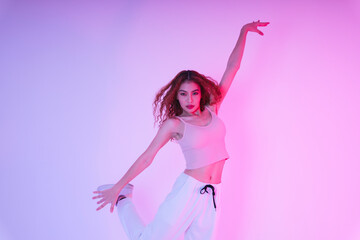 Active asian curly hair girl dancing in neon light at studio indoors.