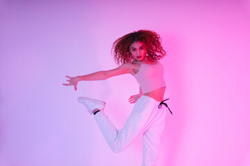 Active asian curly hair girl dancing in neon light at studio indoors.