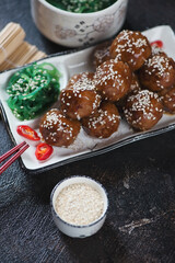 Close-up of fried pork meatballs in teriyaki sauce, vertical shot on a dark brown stone surface