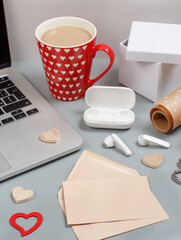 Somebody wrapping valentines gift and writing a message near laptop