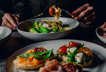 woman eating healthy salad from bowl sitting in cafe