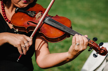 Violin player hands. Violinist playing violin on background of field. Performance on nature. Close up of musical instruments. Shallow depth, vintage style. Musical art, concept passion in music.
