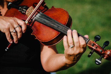 Violin player hands. Violinist playing violin on background of field. Performance on nature. Close up of musical instruments. Classical music professional cello player solo. Unrecognizable person.