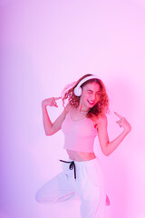 Asian girl in pink cloth listen to music and dance isolate on neon light background.