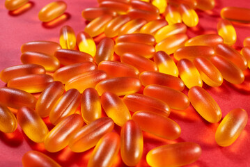 lots of yellow gelatin capsules on a red background. omega viramins, close-up, macro