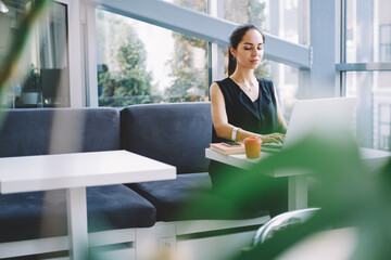 Thoughtful woman with laptop in modern workspace