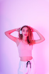 Portrait of asian curly hair girl listen to music with headphone isolate on neon light background.