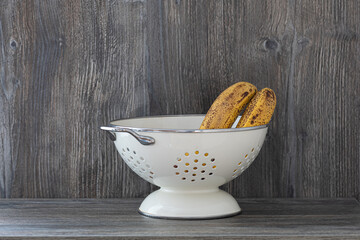 bananas in a white metal vase on a wooden table