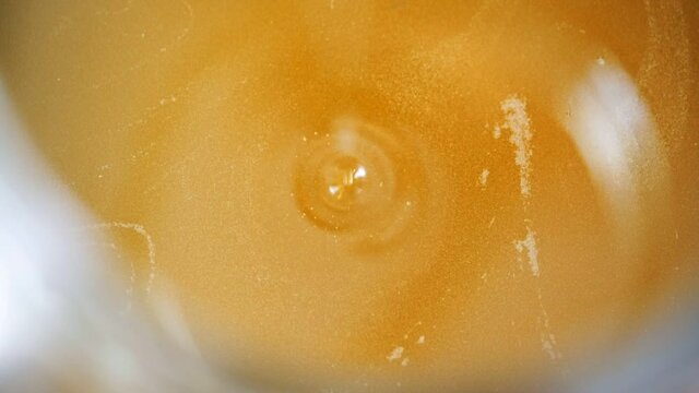 Vegetable oil drips into the container. Close-up.