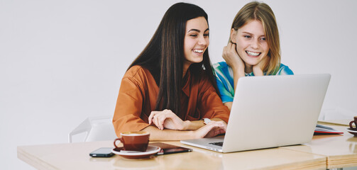 Positive female students using laptop in light workspace
