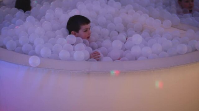 Boy uses indoor ball pit for physical therapy. Pediatric balls pits stimulate or calm as needed for sensory processing disorder regulation of child. Soothing experience for children.