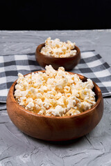 bowl of popcorn on a gray concrete background. The concept of leisure and entertainment. vertical photo