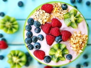 Healthy breakfast - the bowl of oat granola with yogurt, fresh raspberries, blueberries and nuts
