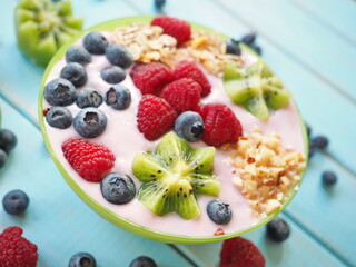 Healthy breakfast - the bowl of oat granola with yogurt, fresh raspberries, blueberries and nuts
