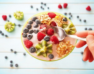Healthy breakfast - the bowl of oat granola with yogurt, fresh raspberries, blueberries and nuts
