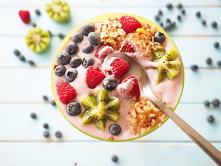 Healthy breakfast - the bowl of oat granola with yogurt, fresh raspberries, blueberries and nuts
