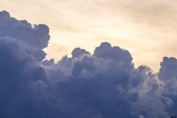 Dark clouds moving in the sky and rapidly changing shapes with the sun in the background at sunset.