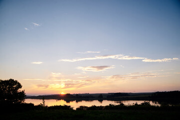 Beautiful lake view during sunset with blue and yellow sky reflection in water. Rural scene. Ecological protection and eco tourism concept. Natural landscape. Isolation in countryside.
