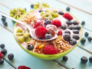Healthy breakfast - the bowl of oat granola with yogurt, fresh raspberries, blueberries and nuts
