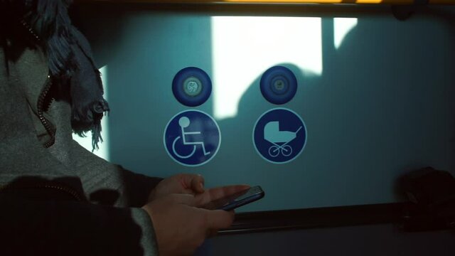 Using the phone in public transport in a passenger seat for disabled and people with kids in strollers, blue icons. Information signs next to emergency call buttons.