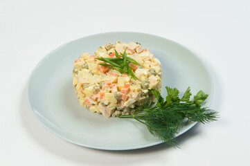Russian traditional holiday Olivier salad served with spring onion scallions, fresh dill, parsley Dish of boiled vegetables. Christmas New Year cold dish served on plate. Object isolated on background