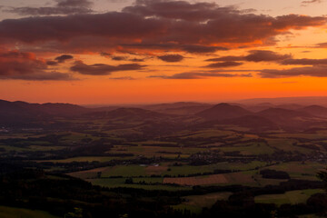 A view of a landscape full of mountains during a golden sunset with the sun on the horizon and a view of the sun from the top of Mount Ondrejnik.