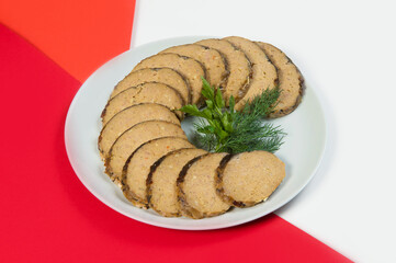 Close up of Stuffed carp fish. Vertical shot of Jewish traditional gefilte fish slices served with fresh green herbs - dill and parsley on red and white abstract background Minced fish with vegetables