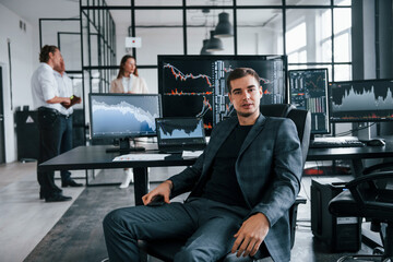 Ordinary office day. Team of stockbrokers works in indoors with many display screens