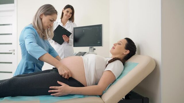 Competent doctor measuring tummy of pregnant woman