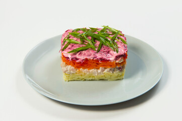 Russian traditional layered vegetable Shuba salad with fish fillet. Herring fish under fur coat. Boiled potato, beetroot, carrot served with spring onion scallions. Dish isolated on background
