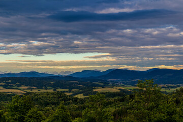 Fototapeta premium The landscape of the Beskydy Mountains from the viewpoint near Jicin during a colorful sunset and dark clouds in the sky and a view of the surrounding landscape.