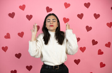 Young beautiful woman over pink background with harts relax and smiling with eyes closed doing meditation gesture with fingers