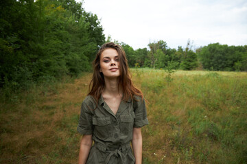 Woman on nature In a green jumpsuit, a smile looks forward to the nature 