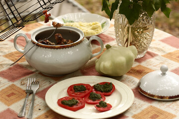 country outdoor still life with tureen, patisson, mashed potato and tomato with pesto sauce