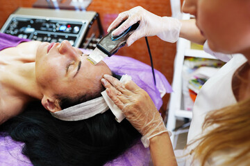 Ultrasonic cleaning of the face treatment by the woman in SPA center
