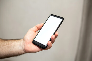 Close-up of hand holding smartphone on gray background.