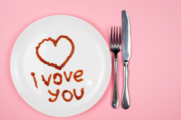 Ketchup on a white plate says I love you . Concept of the holiday on February 14.