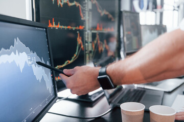 Close up view of man's hand that points at part of stock graph on display