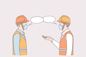 Social distance at work during pandemic concept. Men workers in medical protective face masks standing and keeping distance during talking together on work in factory to prevent Covid-19 virus 