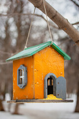Bird feeders of handmade on tree trunk in park. Homemade grain feeder for wintering birds
