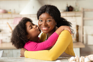 Happy Mother's Day. Little Black Girl Kissing Her Happy Mom In Kitchen
