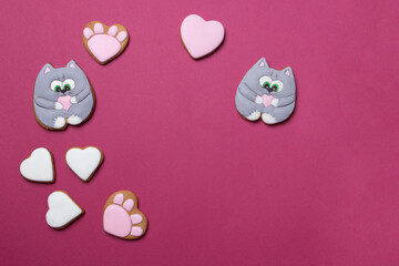Valentine cookies in form of cats on red colored paper background with copyspace