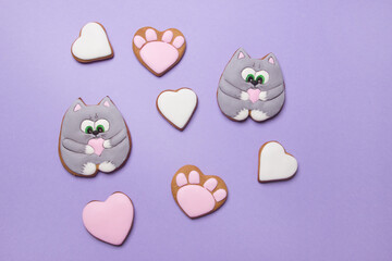 Valentine cookies in form of cats on violet colored paper background