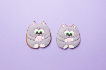 two valentines cookies in form of cats on purple colored paper background