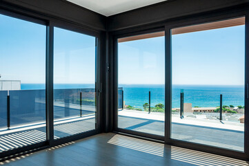 Fototapeta na wymiar Empty room with large panoramic windows overlooking the sea. Room after major renovation.