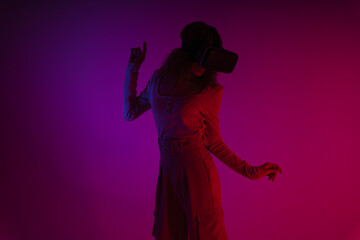 Young woman wear virtual reality VR goggles in neon light background.