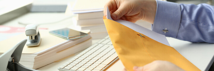 Cropped head of male hands holding pack of papers while working with computer in office