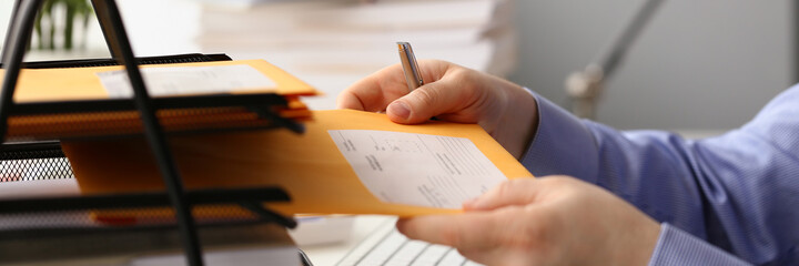 Close up cropped head of male hands holding folder with documents while sitting at desk with...