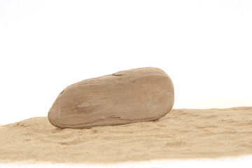 Driftwood on sand isolated on white background. Piece of coastal weathered wood on sand dune.